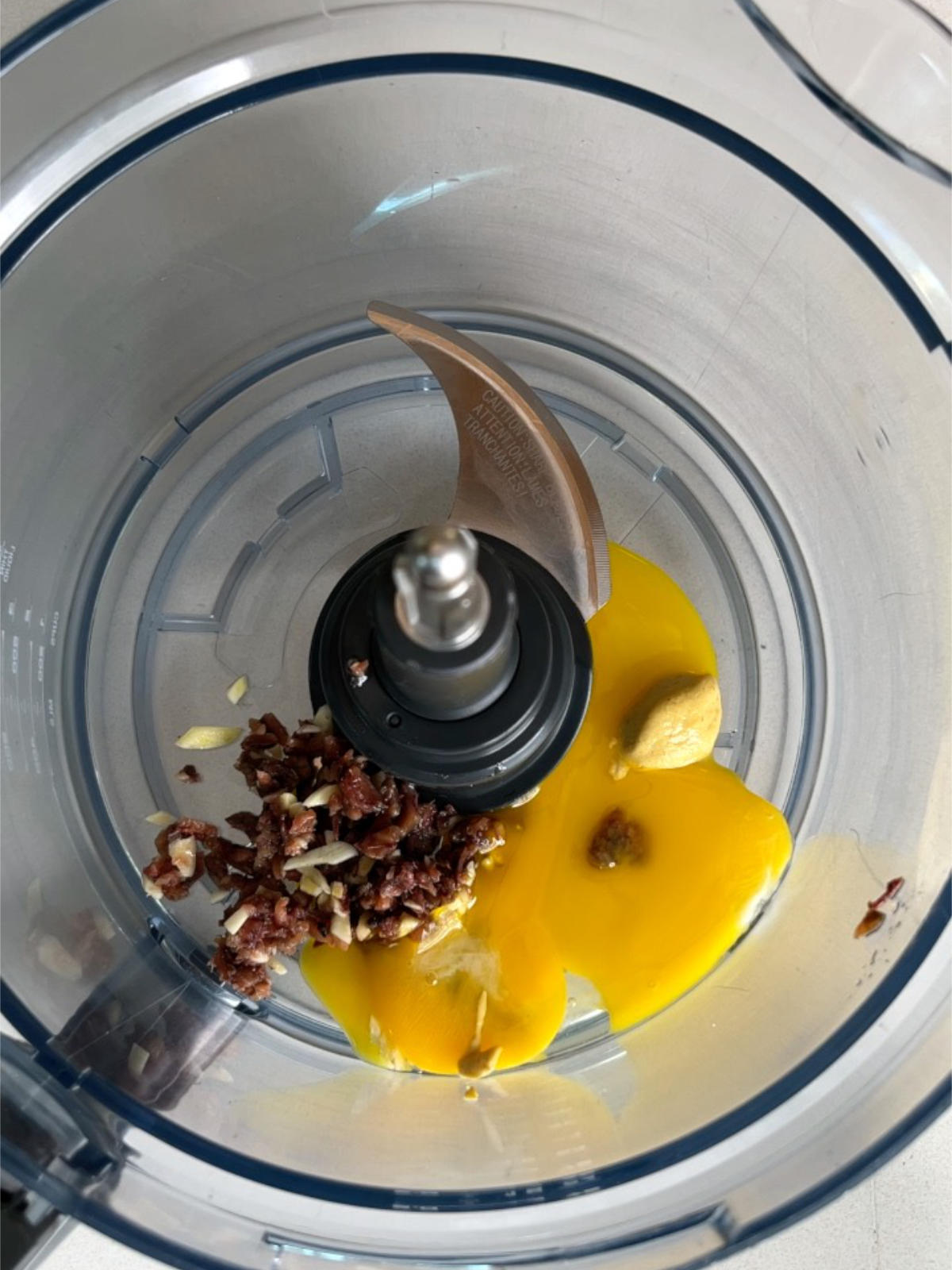 Chopped anchovy, musard, and egg yolks in a food processor bowl.