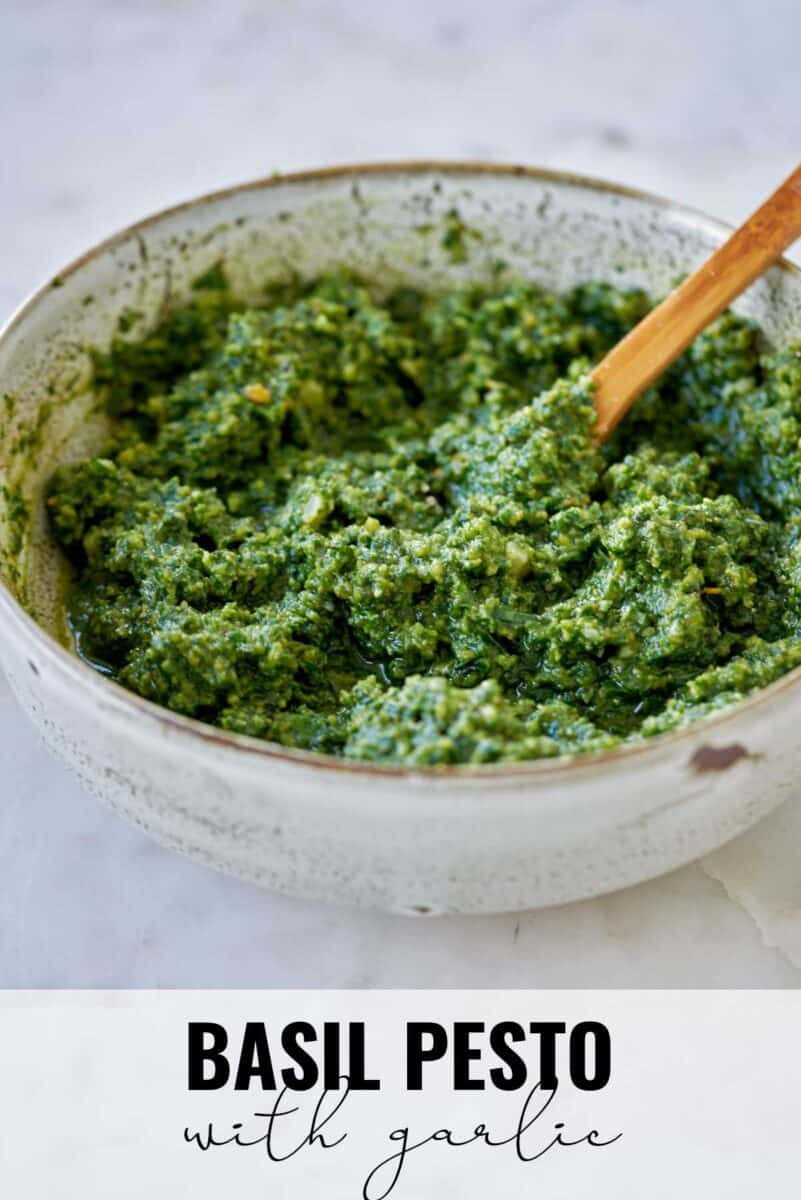 Bowl with basil pesto and a wooden spoon.