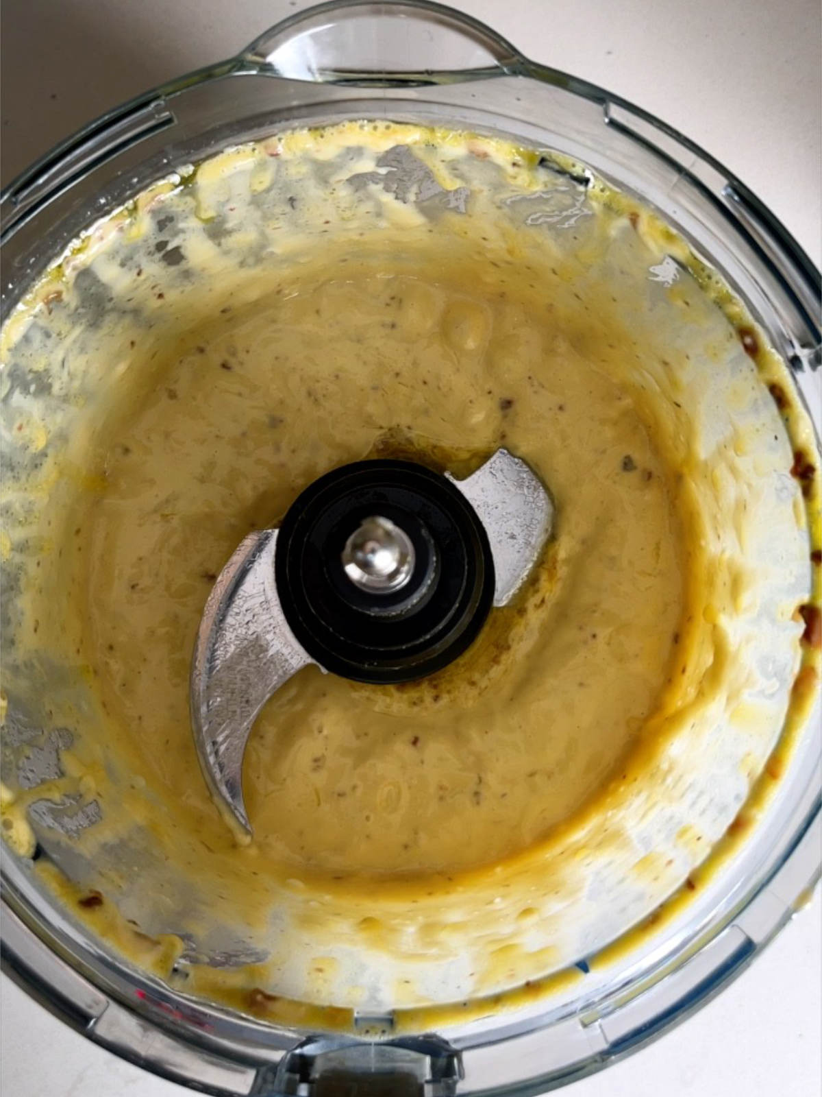 Caesar salad dressing in a food processor bowl.