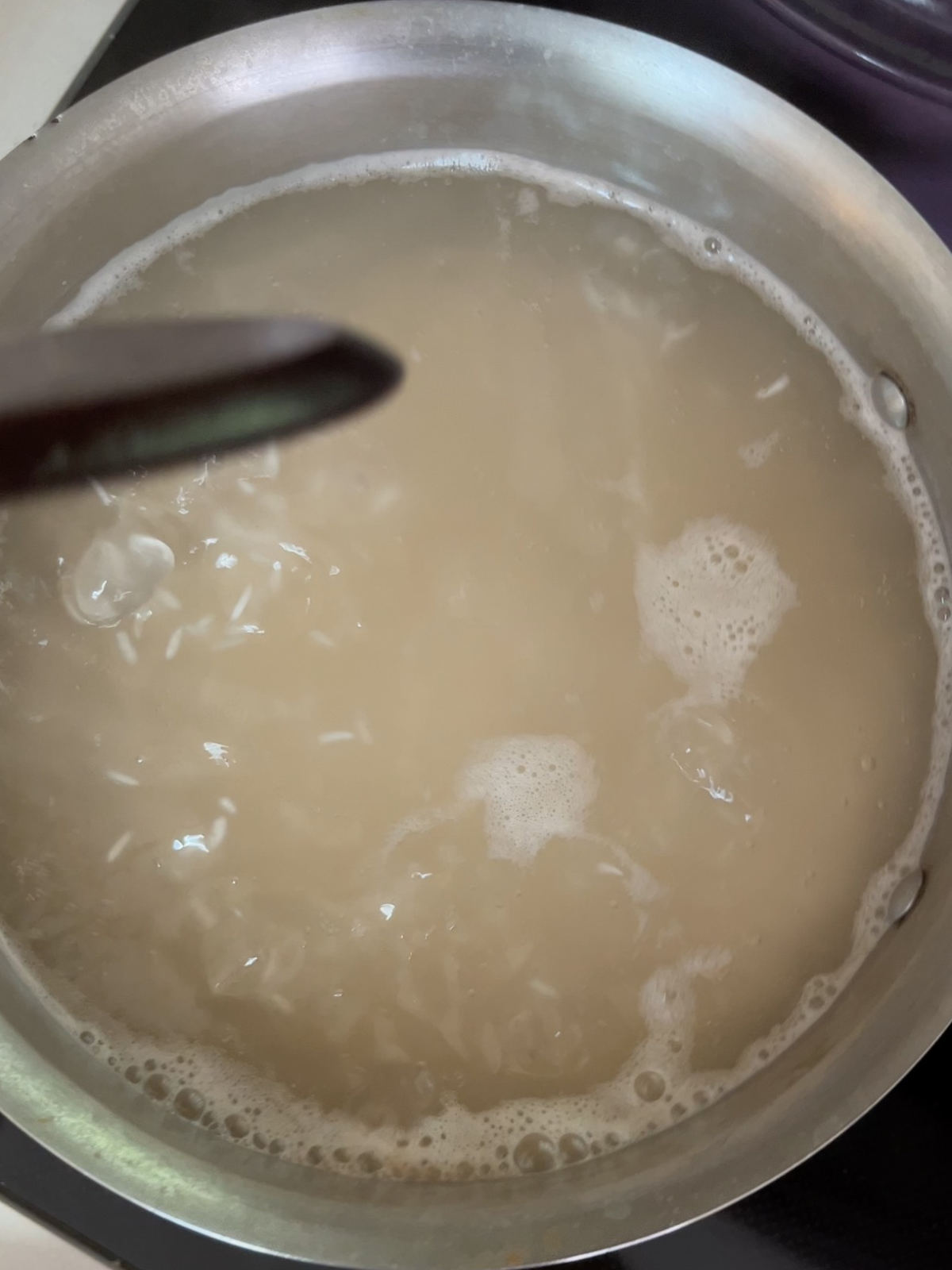 Pot of water with rice coming to a boil.