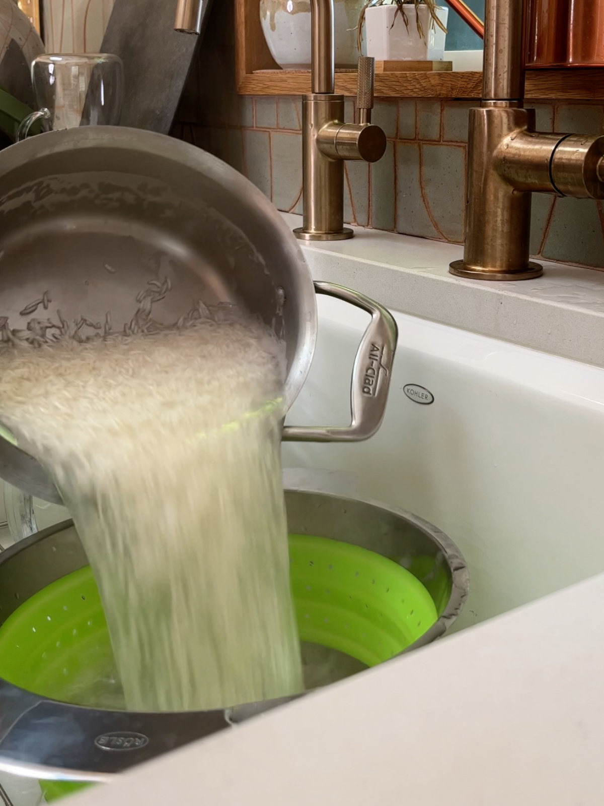 Pouring rice into a green colander from a metal pot.