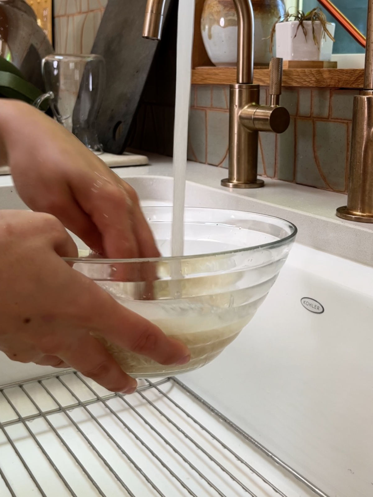 Washing rice in a glass bowl in a white sink.