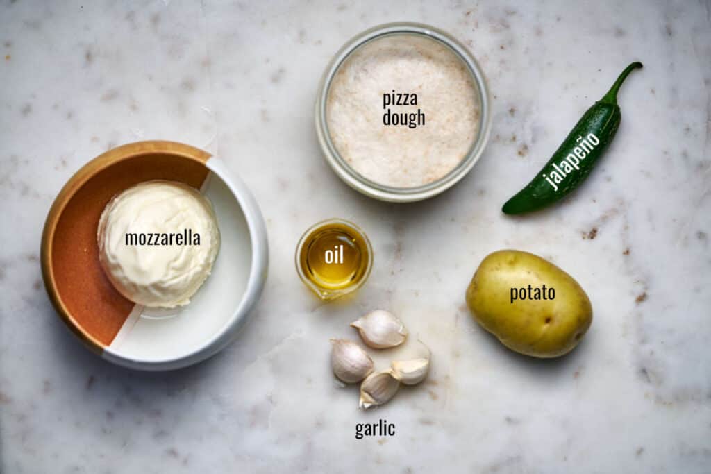 Ingredients for potato jalapeño pizza including mozzarella, pizza dough, and garlic.