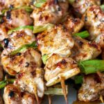 Chicken kabobs on skewers with scallions.