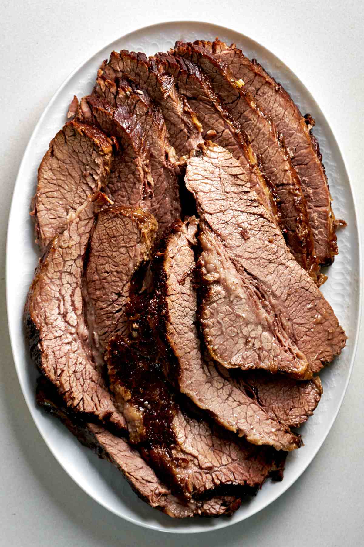 Sliced brisket on a white oval serving plate.