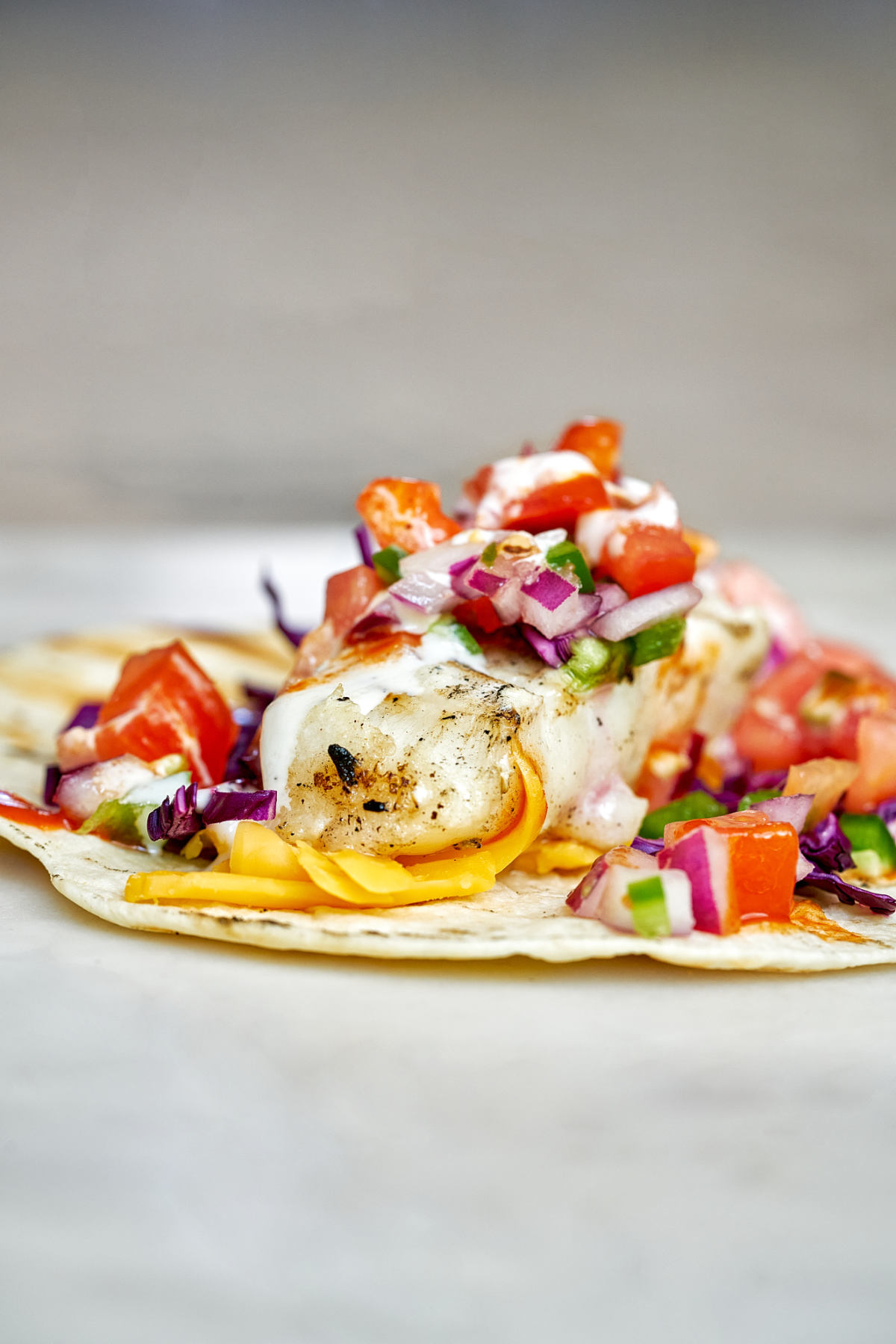 Close up of a white fish taco with pico de gallo and red onion topping.
