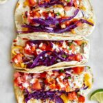 Three fish tacos with red cabbage and salsa.