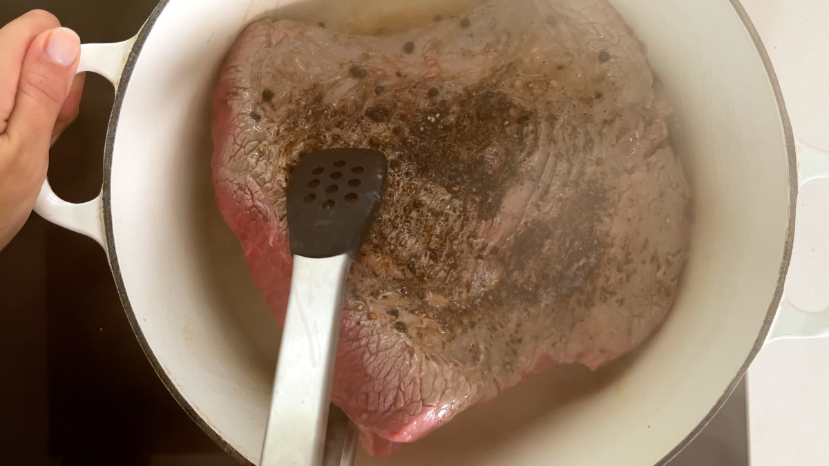 Searing meat in a white dutch oven pot.