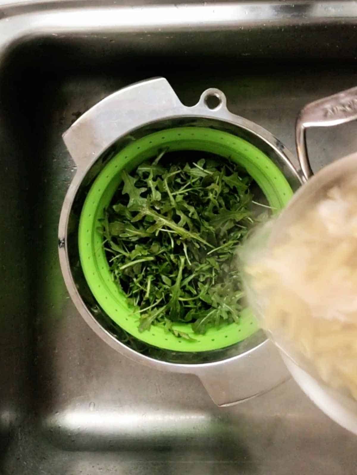 Colander with greens in a sink.