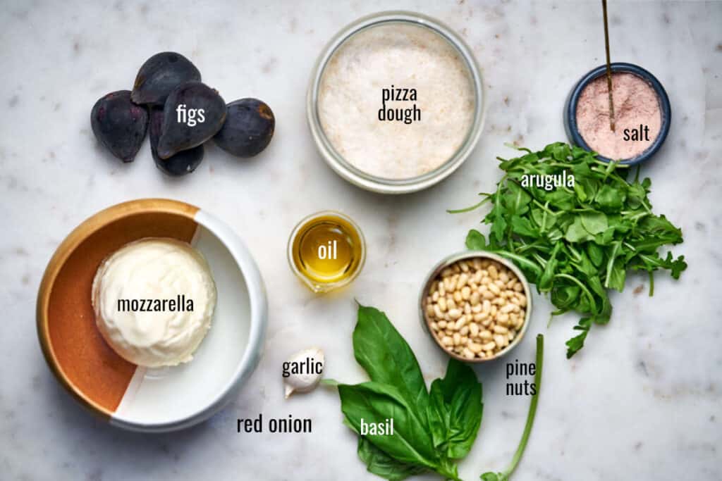 Ingredients for fig pizza including pesto ingredients and arugula.