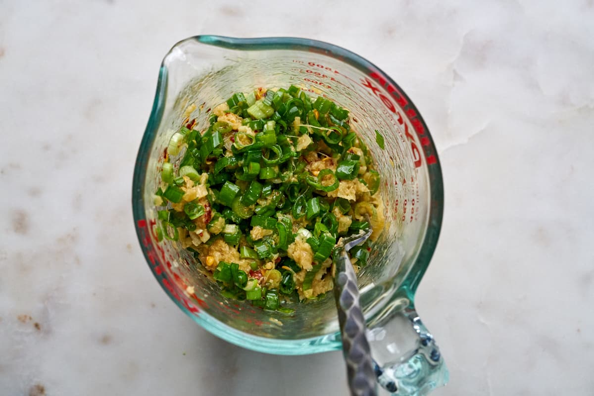 Scallions and ginger in a liquid measuring cup.