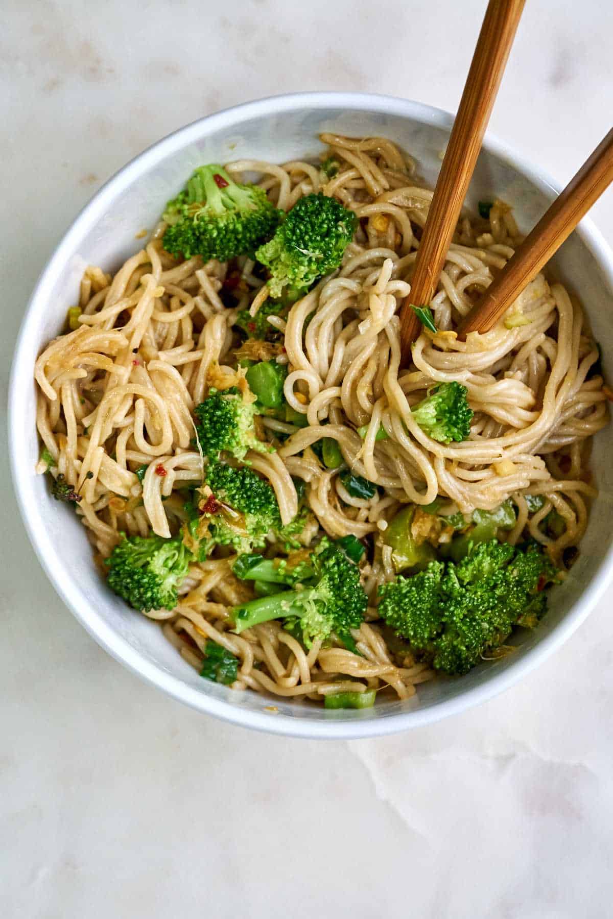 Noodles and broccoli in a bowl with chopsticks.