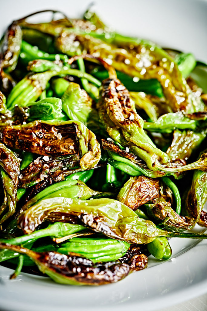 Close up shot of blistered shishito peppers.