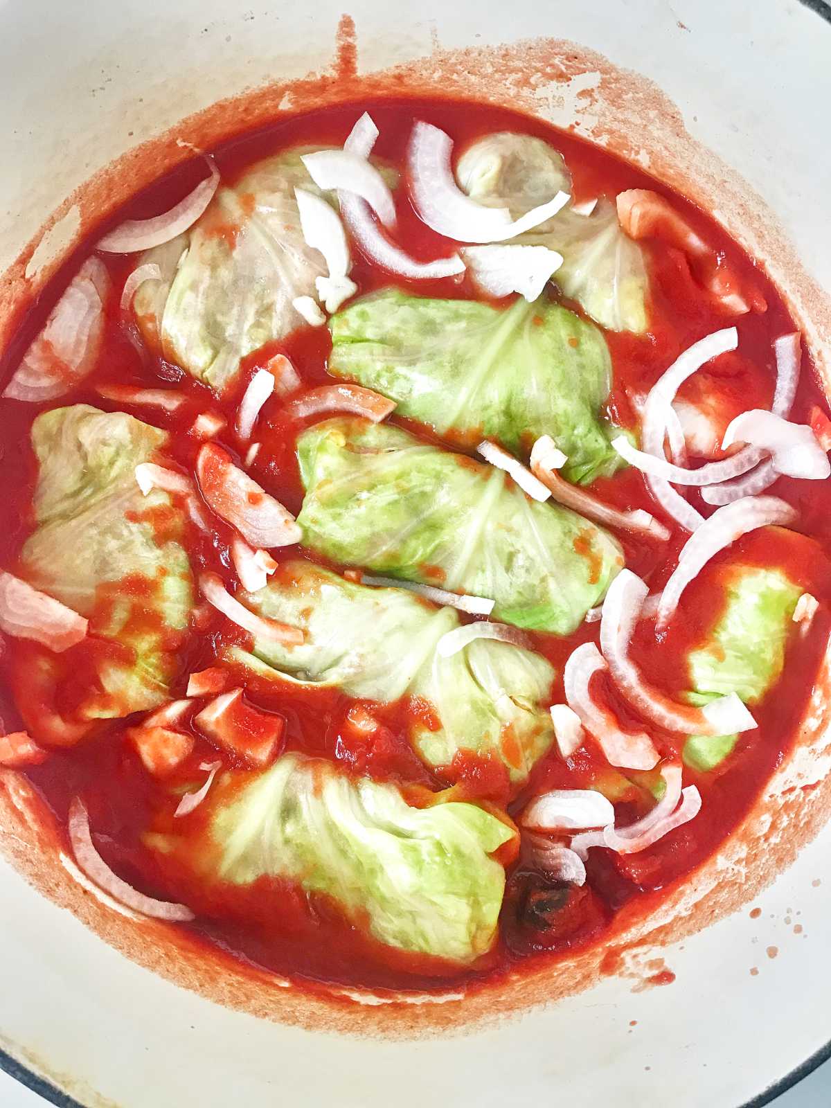 Cabbage rolls in red sauce with onions.