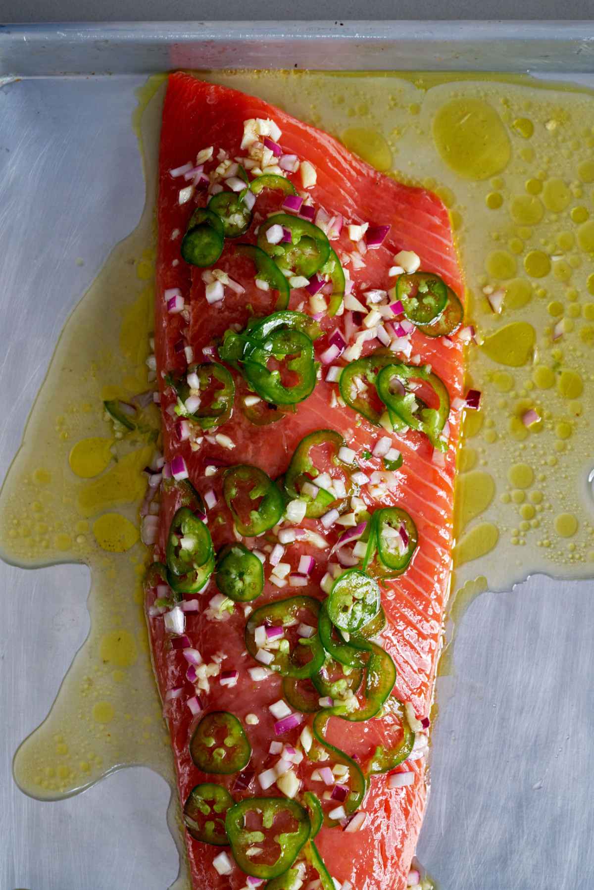 Raw salmon covered in jalapenos and olive oil.