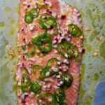 Cooked salmon on a baking dish with jalapeno slices.