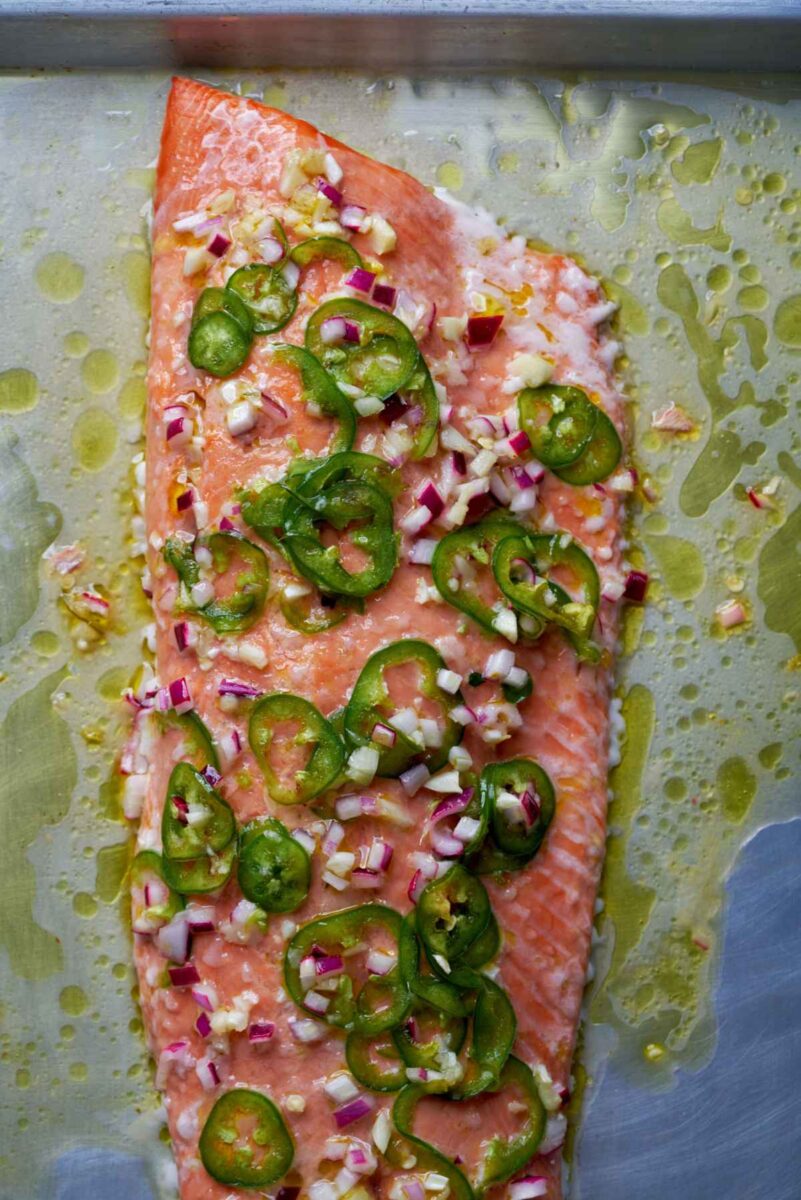 Cooked salmon on a baking dish with jalapeno slices.