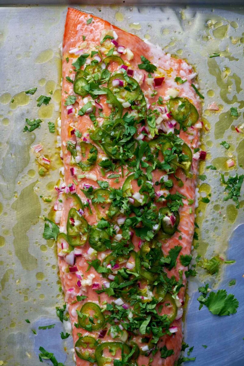 Cooked salmon covered in cilantro on a baking dish.