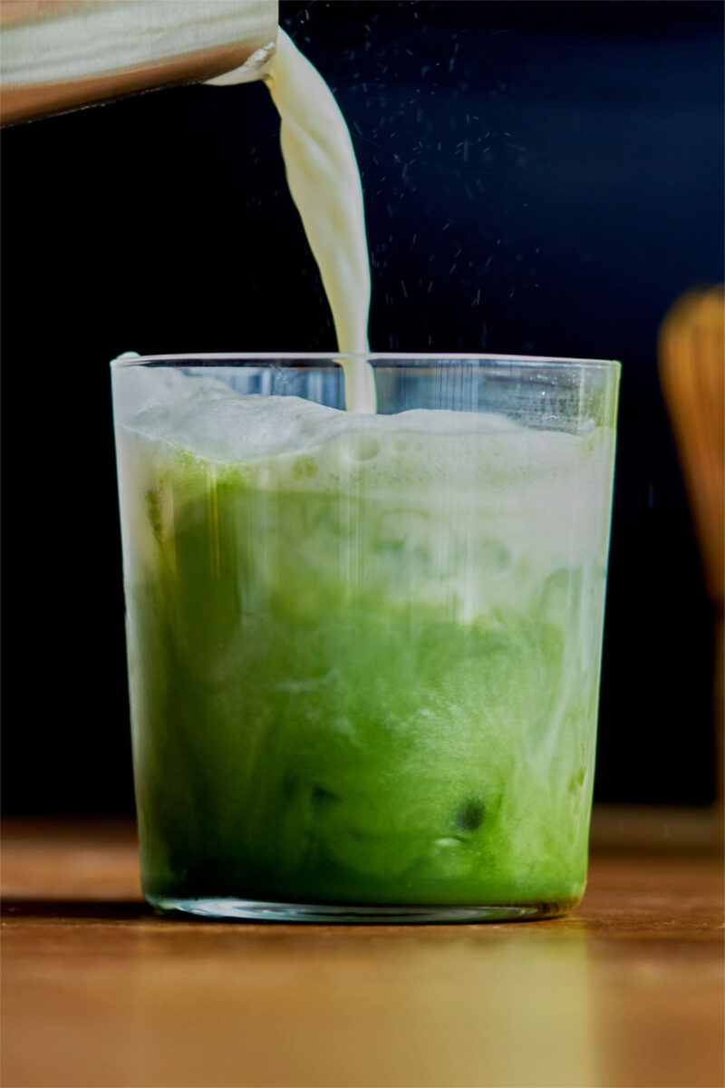 Pouring milk into a matcha green tea latte.