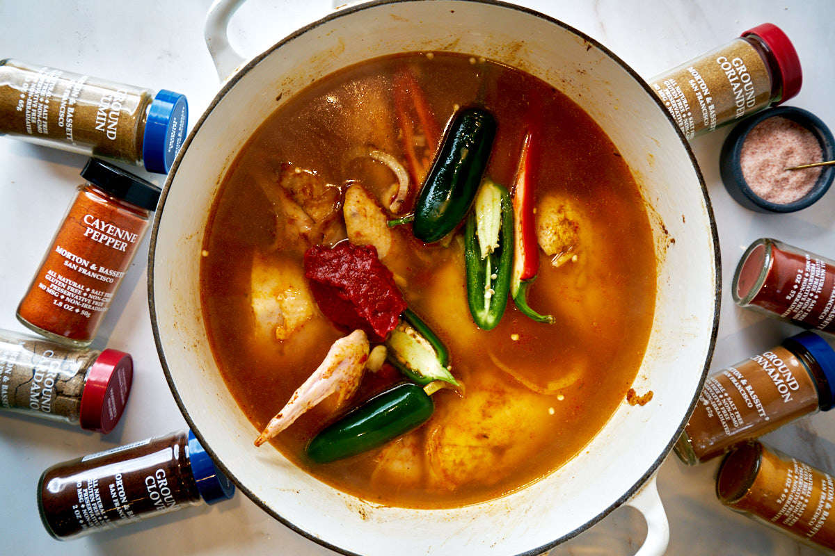 Soup in a pot next to spice bottles.