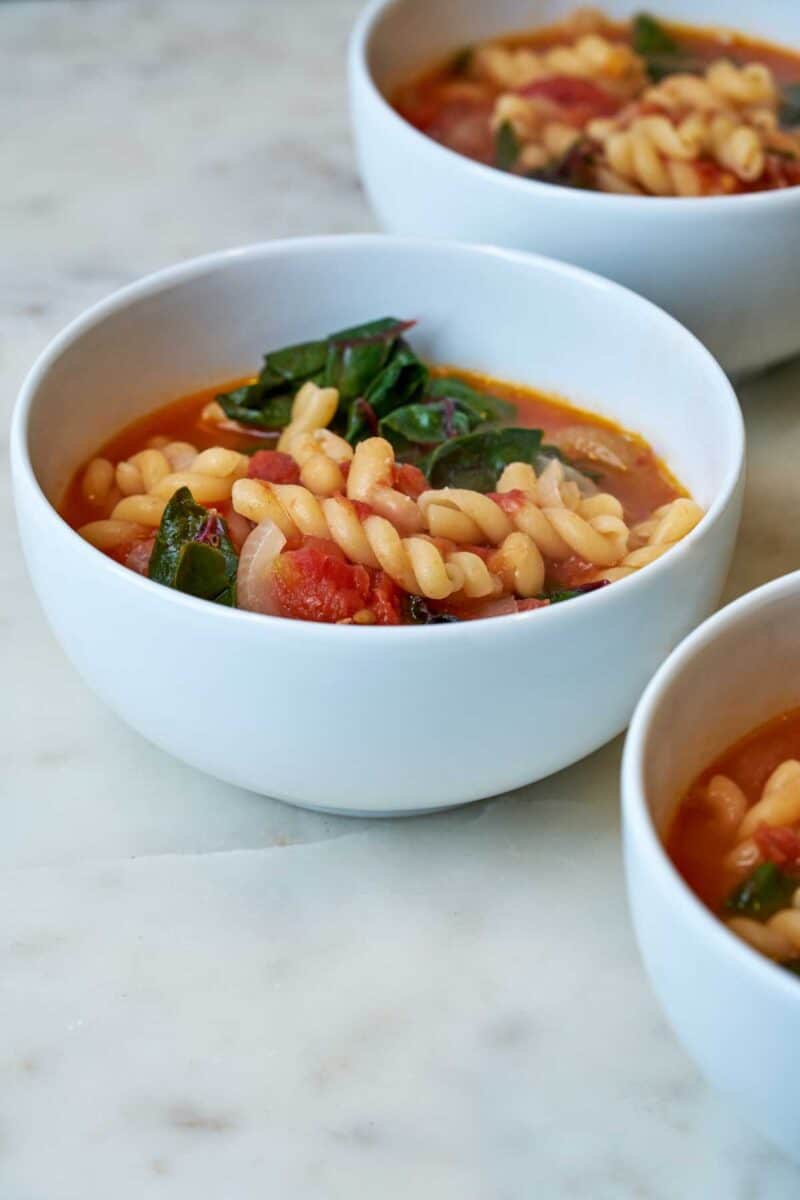 Bowl of red soup with noodles.