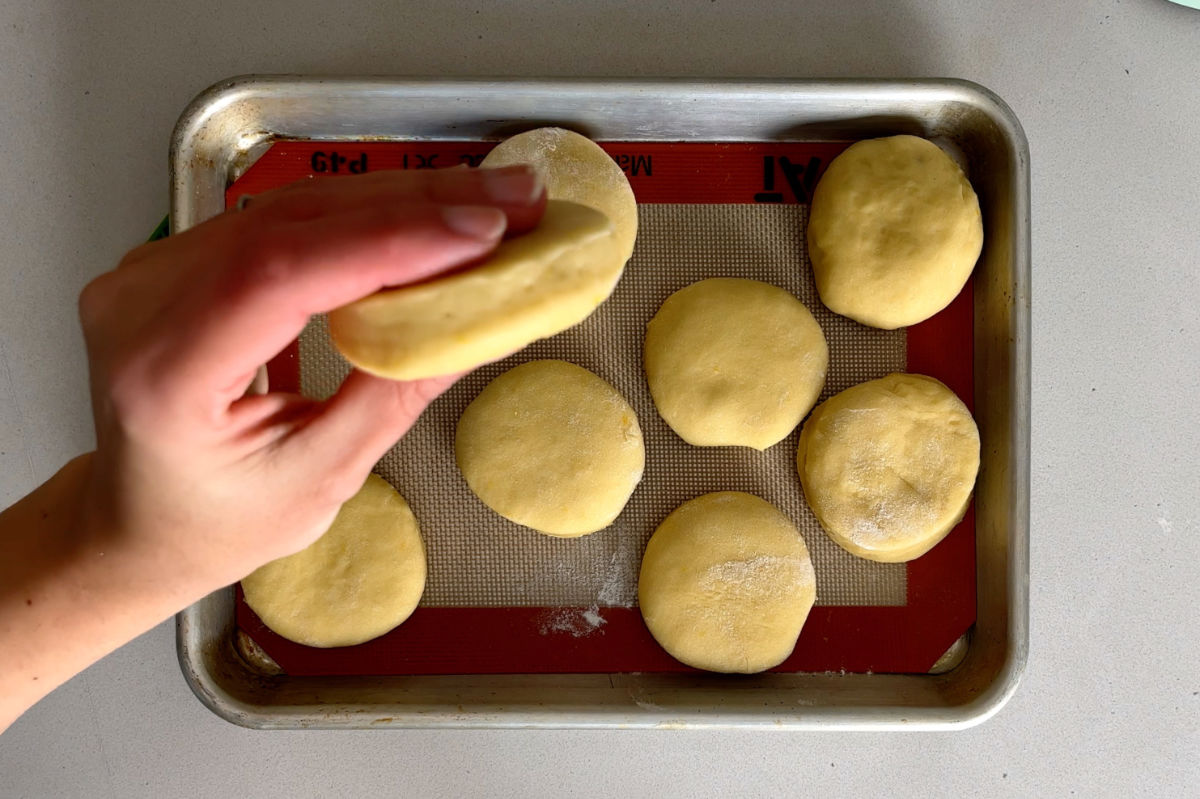 Raw doughnuts on a baking sheet.