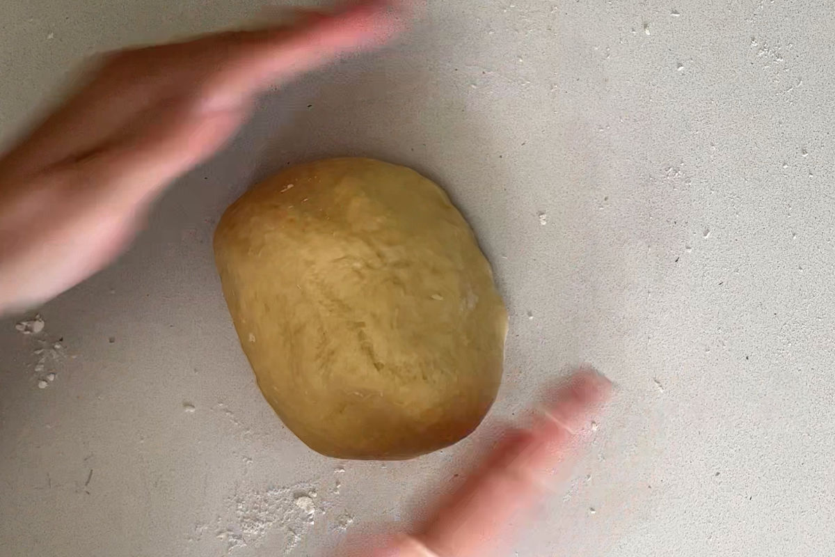 Hands rolling a ball of dough.