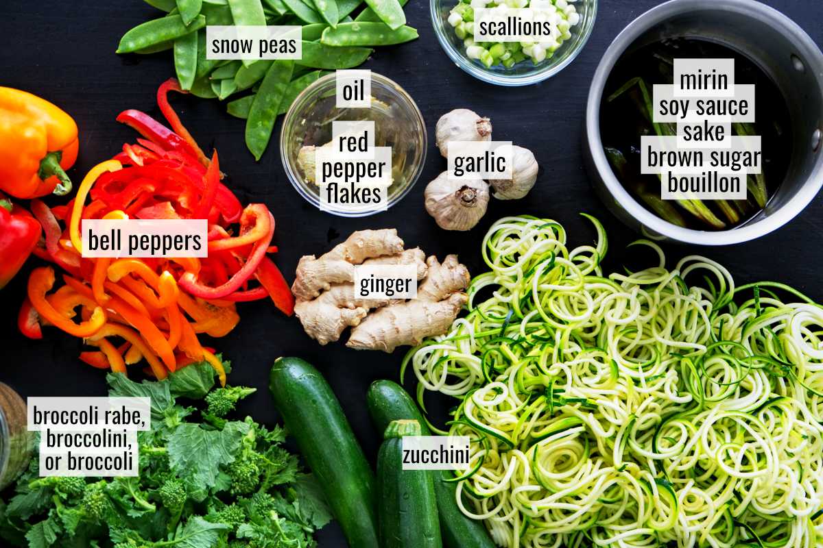 Prepped vegetables next to whole vegetables and a pot of sauce.