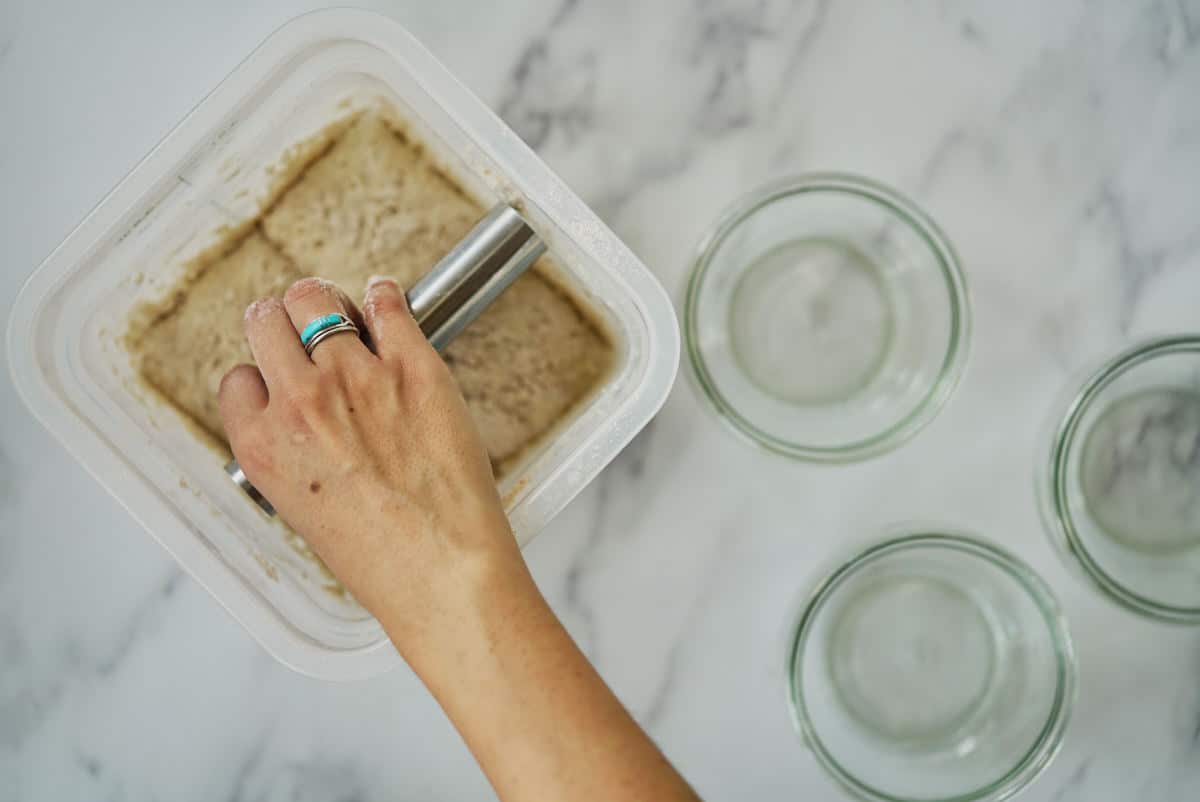 Hand cutting container of dough into four parts.