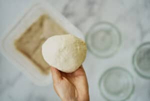 Hand holding a ball of pizza dough.