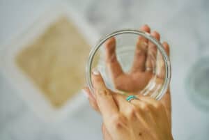 Two hands oiling a glass jar.