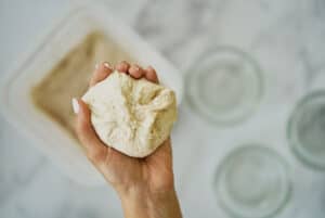 Hand holding dough that has been pinched.