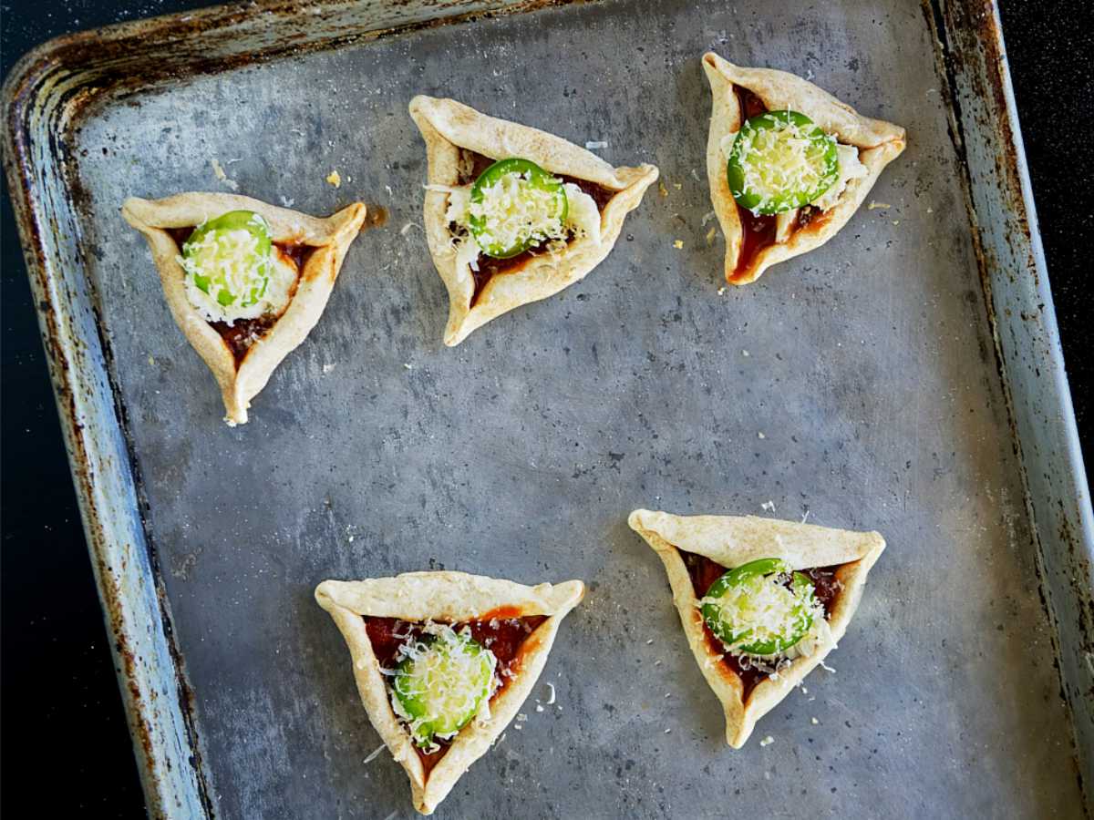 Mini triangular pizzas on a baking sheet.