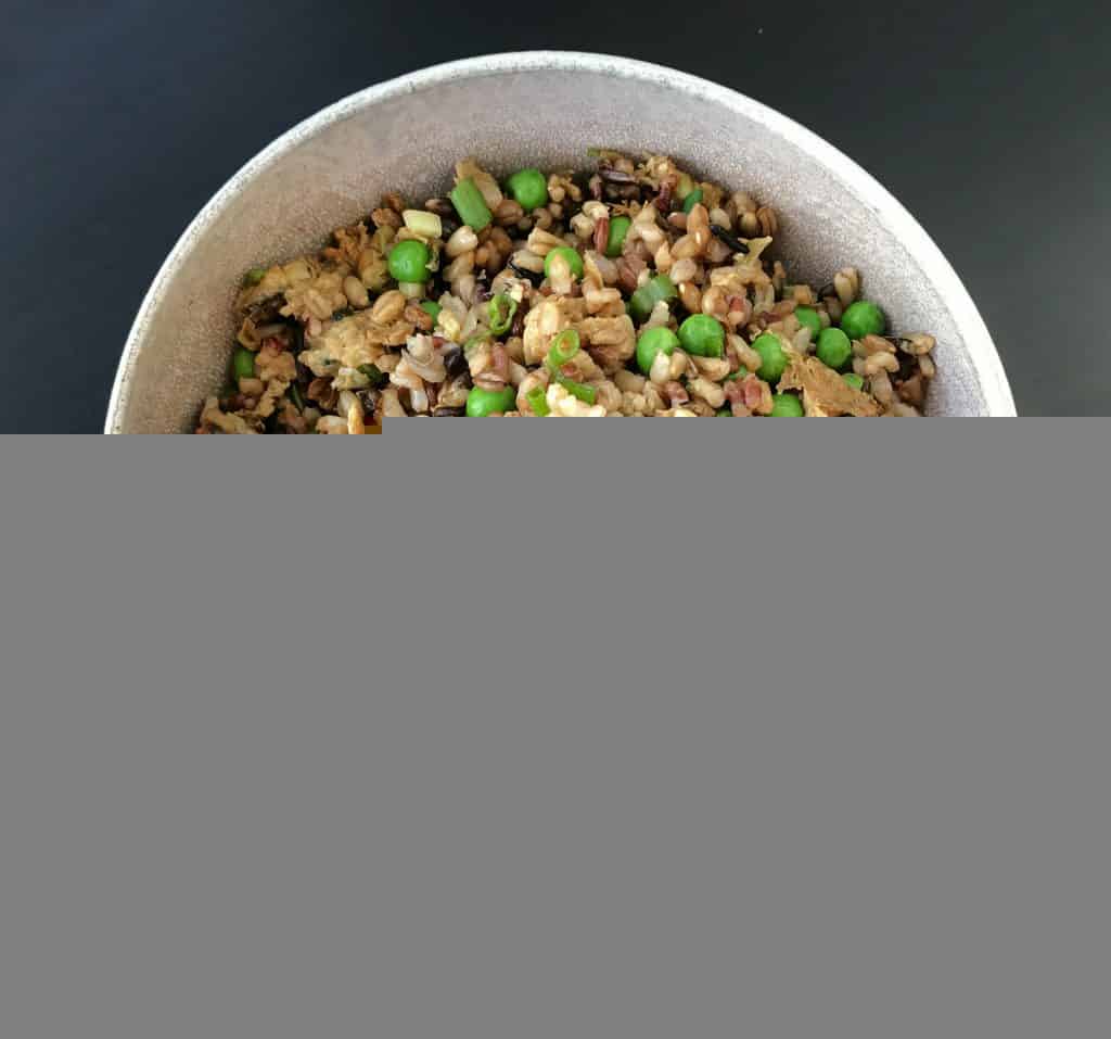 Bowl with fried rice and peas on a black background.