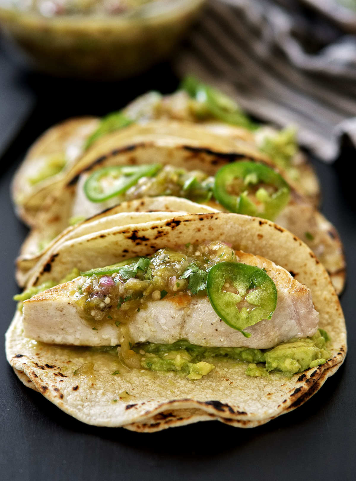 Front view of a row of fish tacos.