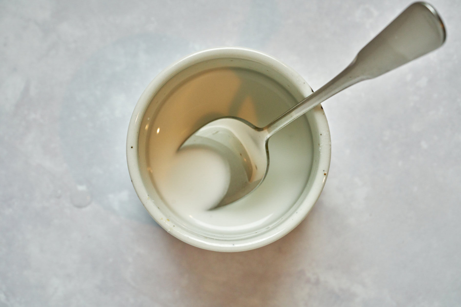 White liquid in a small bowl with a spoon.