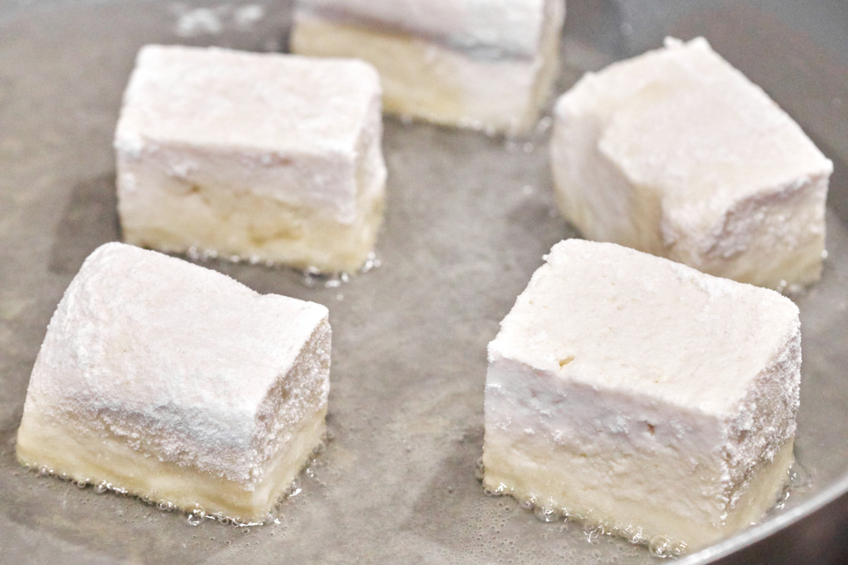 Tofu frying in a non-stick pan.