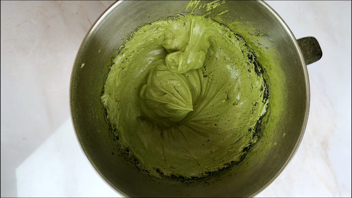 Green macaron batter in a metal stand mixer bowl.