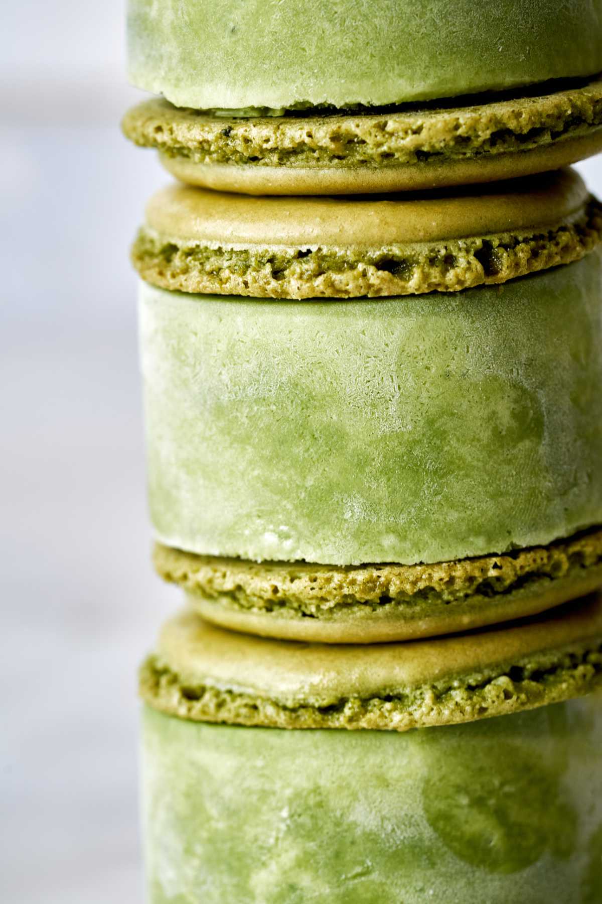 Stack of green macaron ice cream sandwiches.