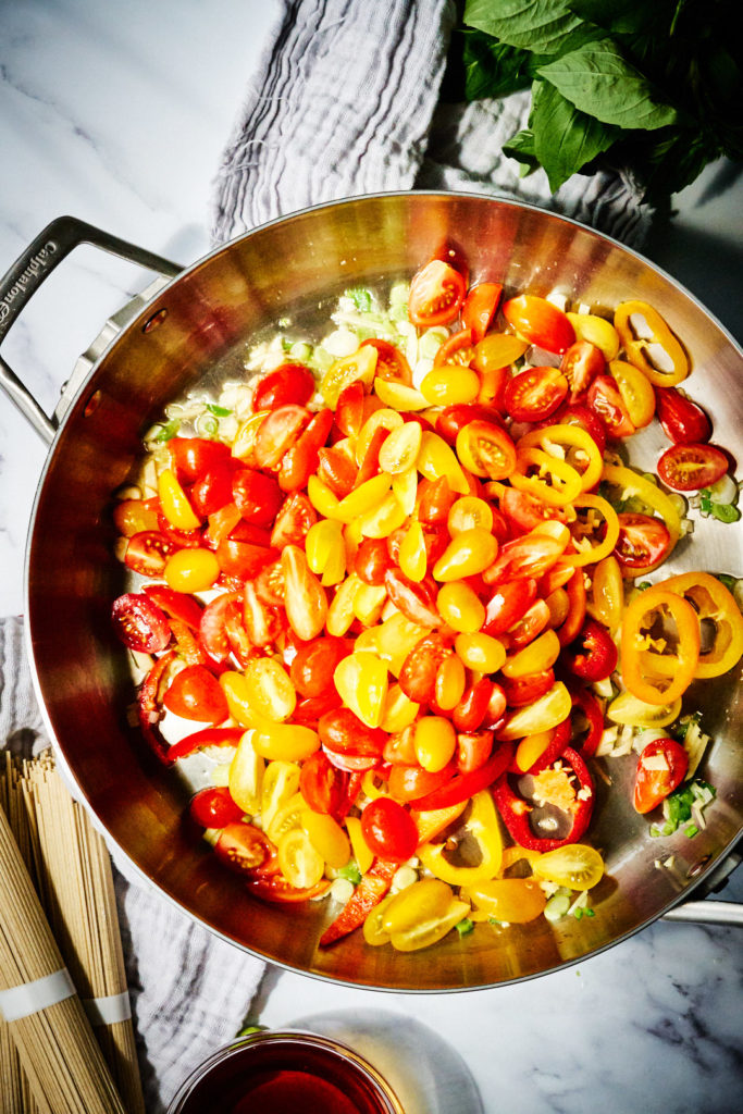 Fry pan full of multicolored tomatoes and peppers.