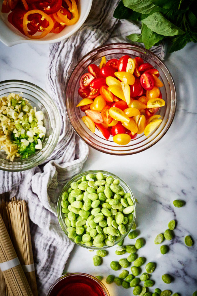 Ingredients for a soba stir fry on a marble countertop.