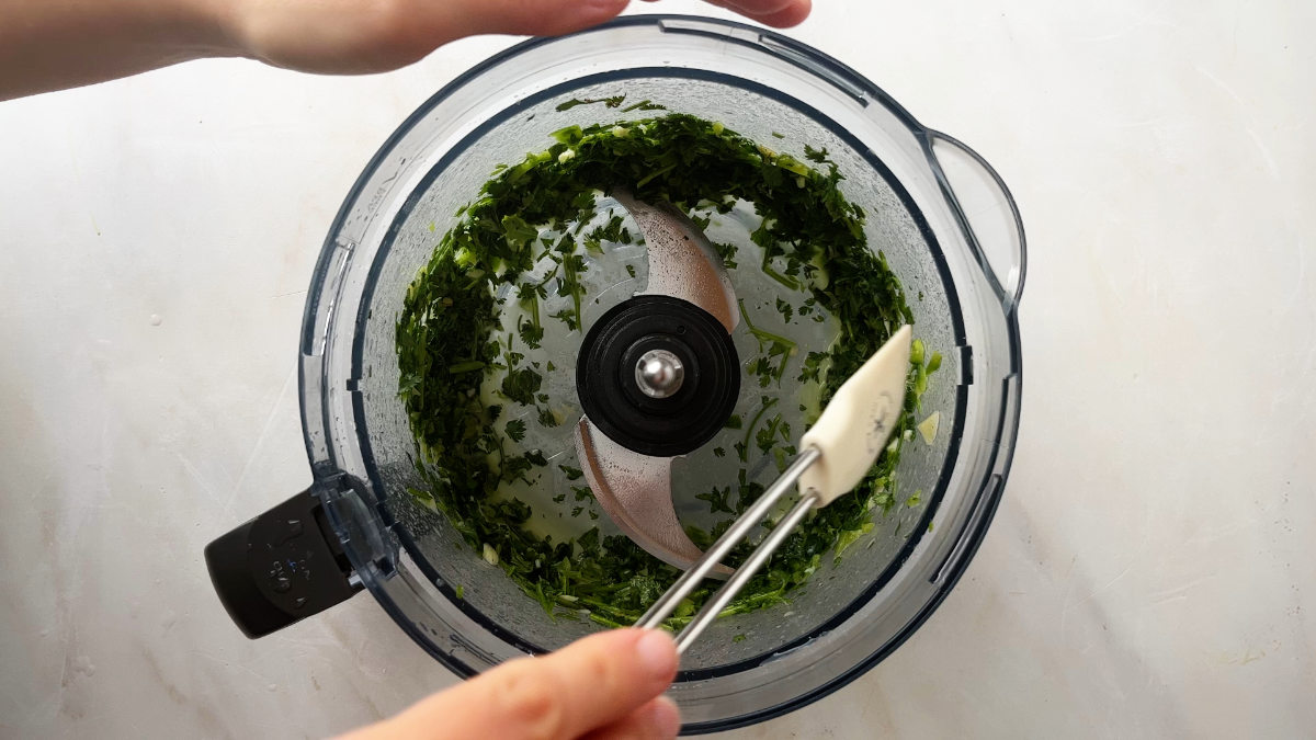 Chopped herbs in a food processor bowl.