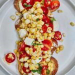 Corn and tomato salad on top of slices of baguette.