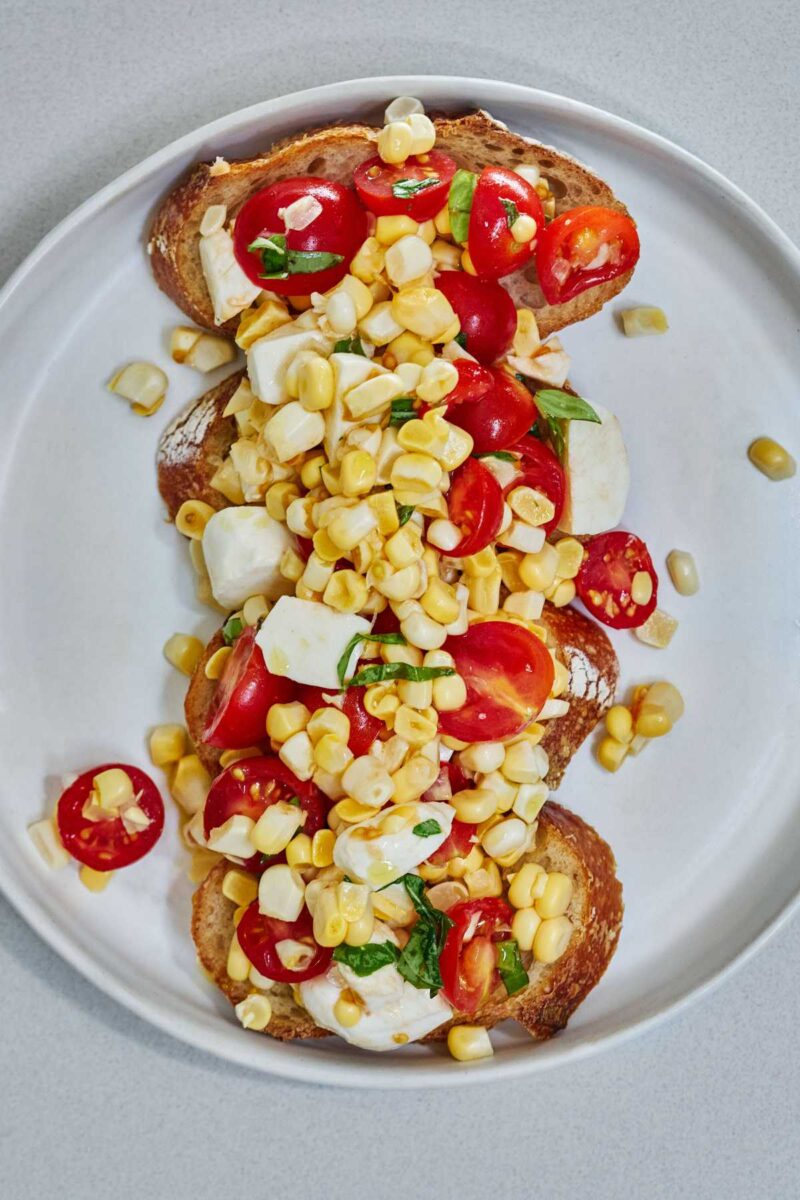 Corn and tomato salad on top of slices of baguette.
