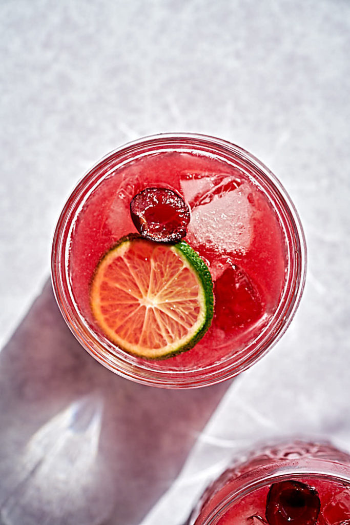 Pink cocktail with cherry and lime.