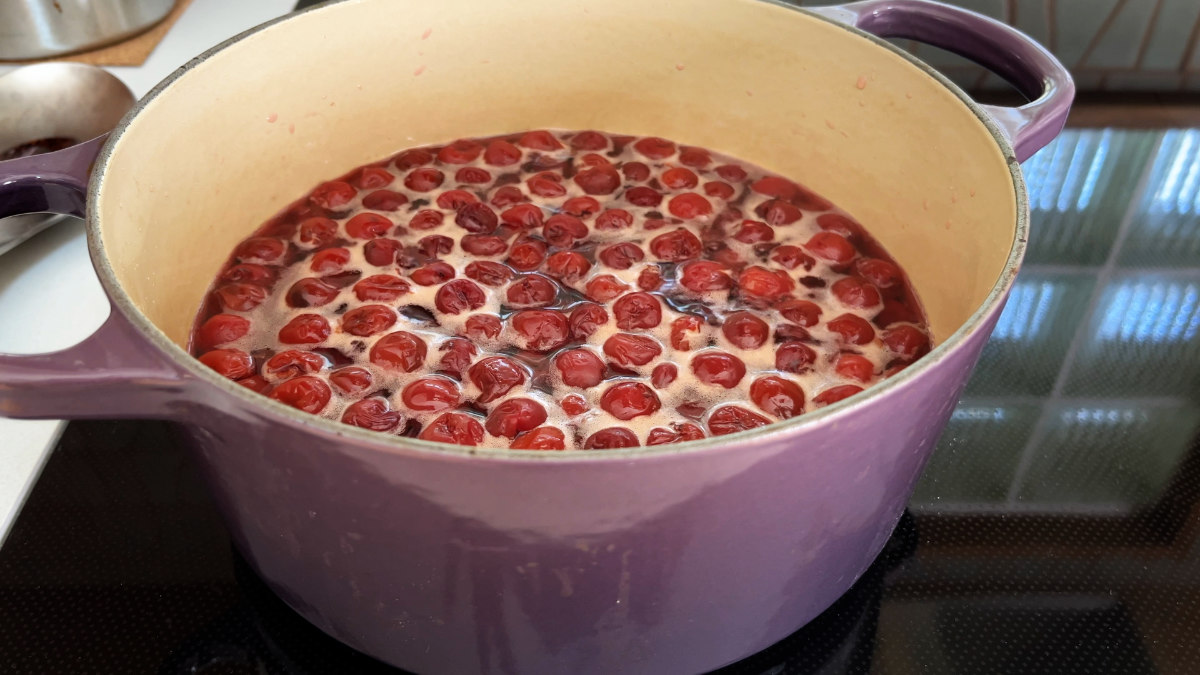 Cherries simmering in a pot on a cooktop.