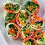 Small cut pieces of salad rolls next to dipping sauce.