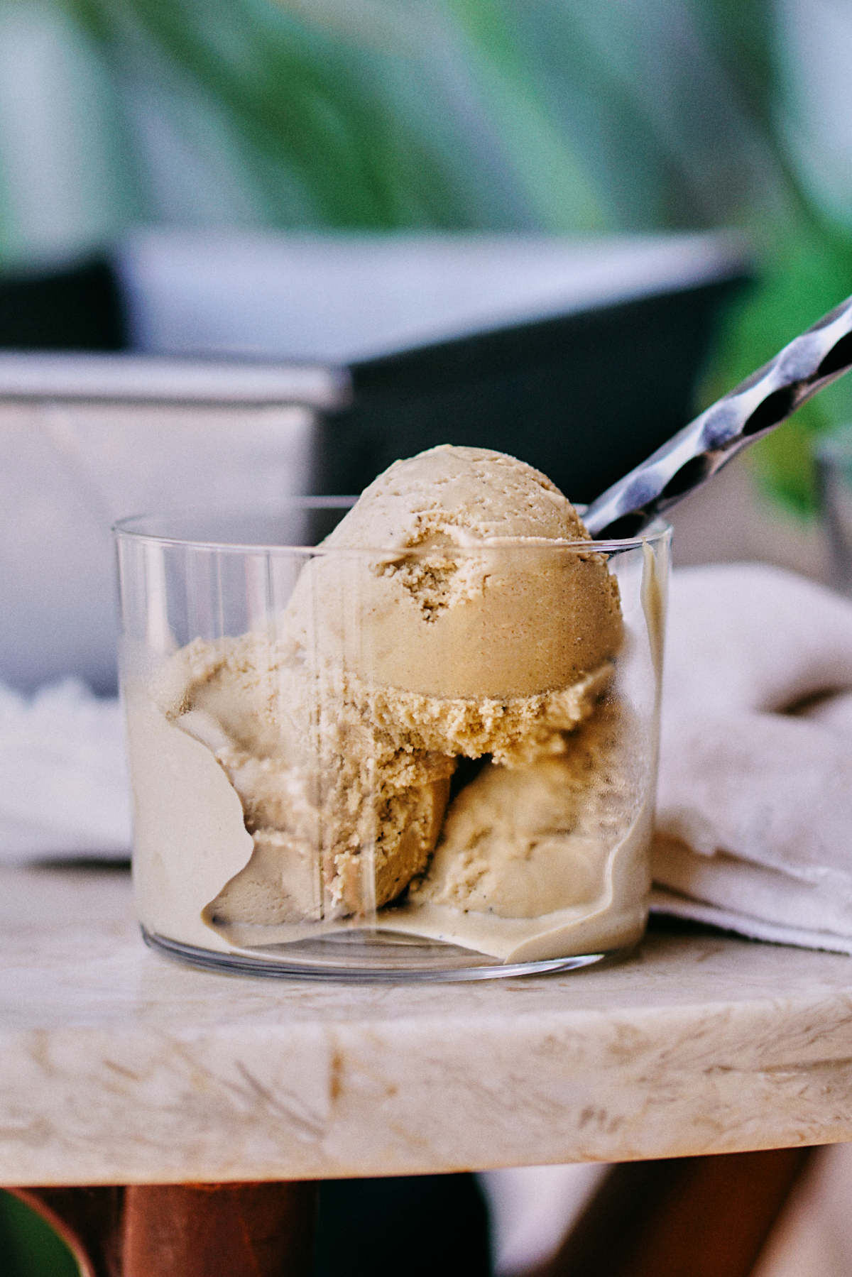 Melting ice cream in a glass cup with a spoon on a marble table.