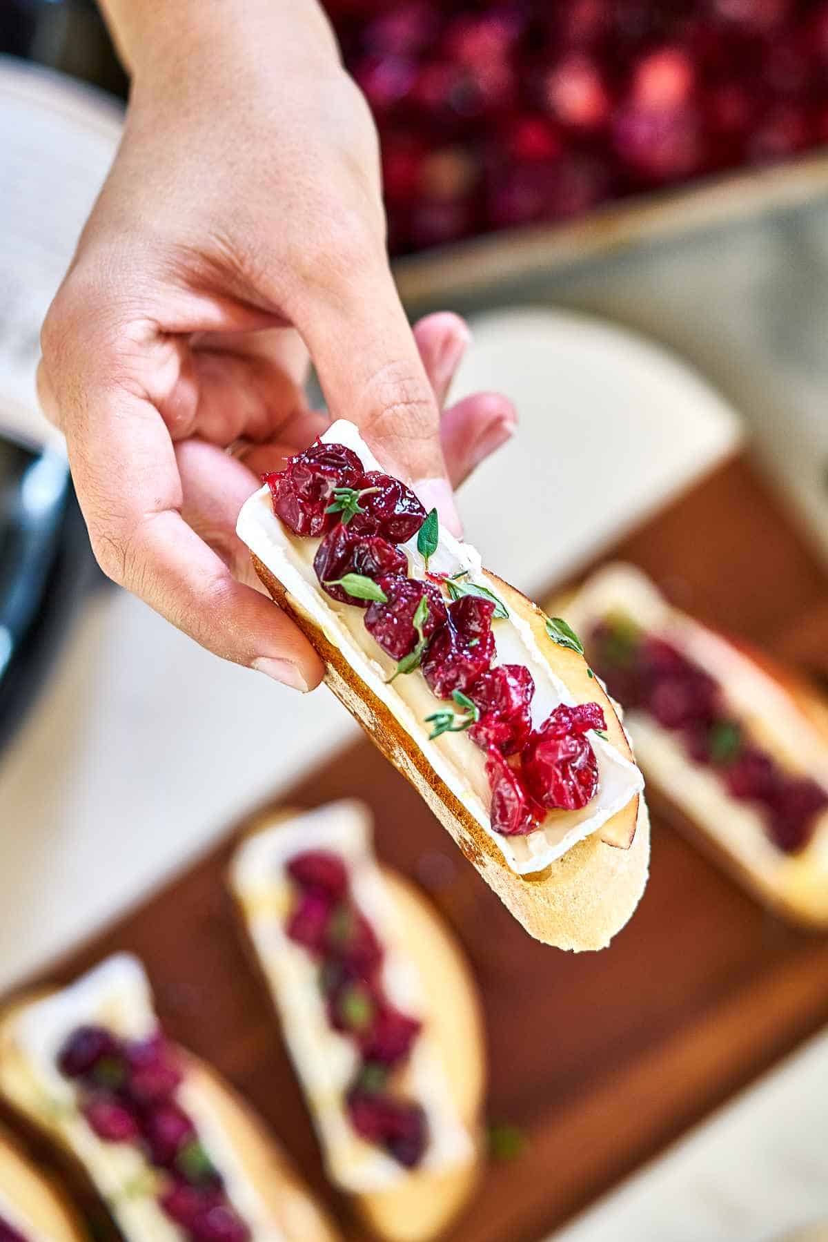 Hand holding a piece of crostini.