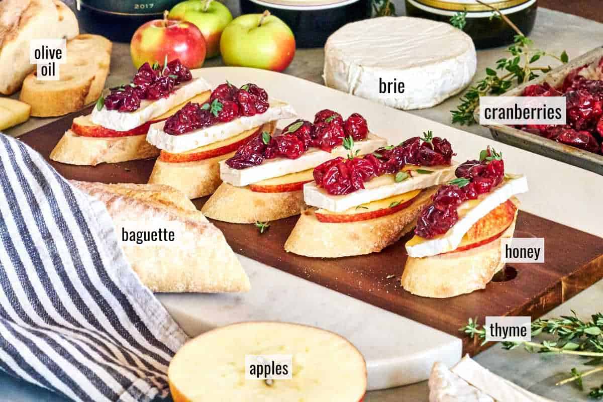 Crostini on a cutting board surrounded by ingredients.